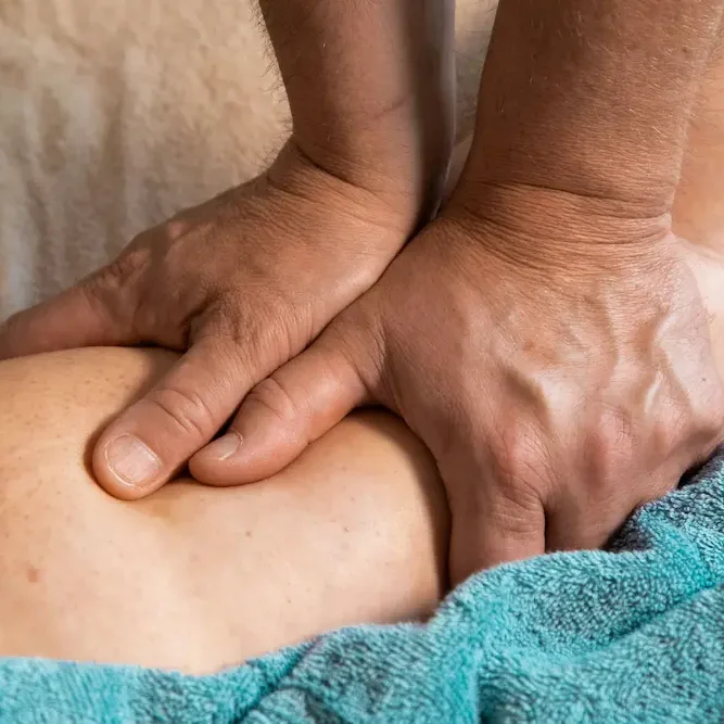 Manos del fisioterapeuta realizando masaje terapéutico a domicilio en Valencia
